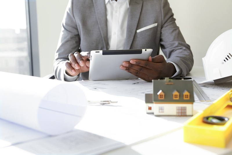 Selective focus. Design and architecture. Cropped shot of African architect holding digital tablet, developing new real estate project, sitting at desk with architectural tools and scale model house selective-focus-design-architecture.jpg