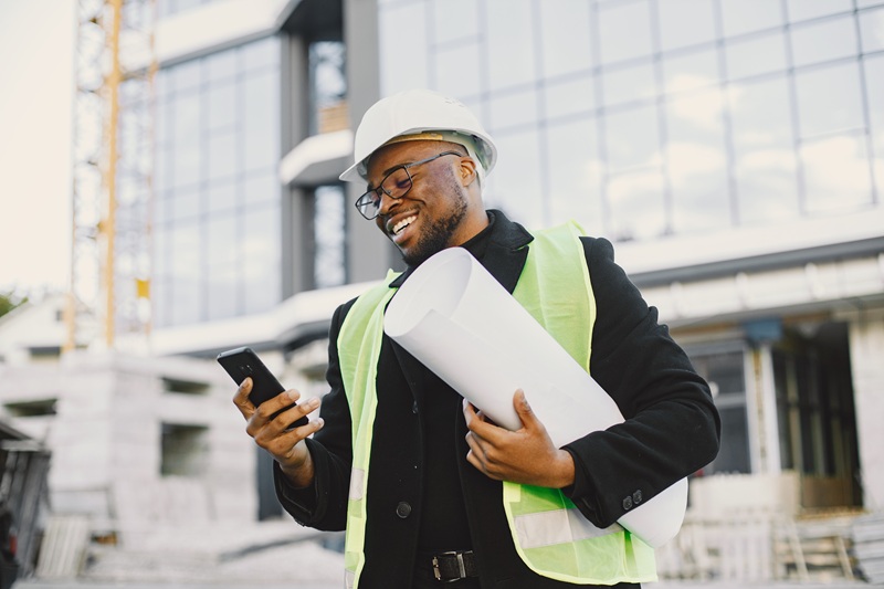 Black architect with project talk by phone young-black-race-man-with-blueprint-stading-near-glass-building.jpg